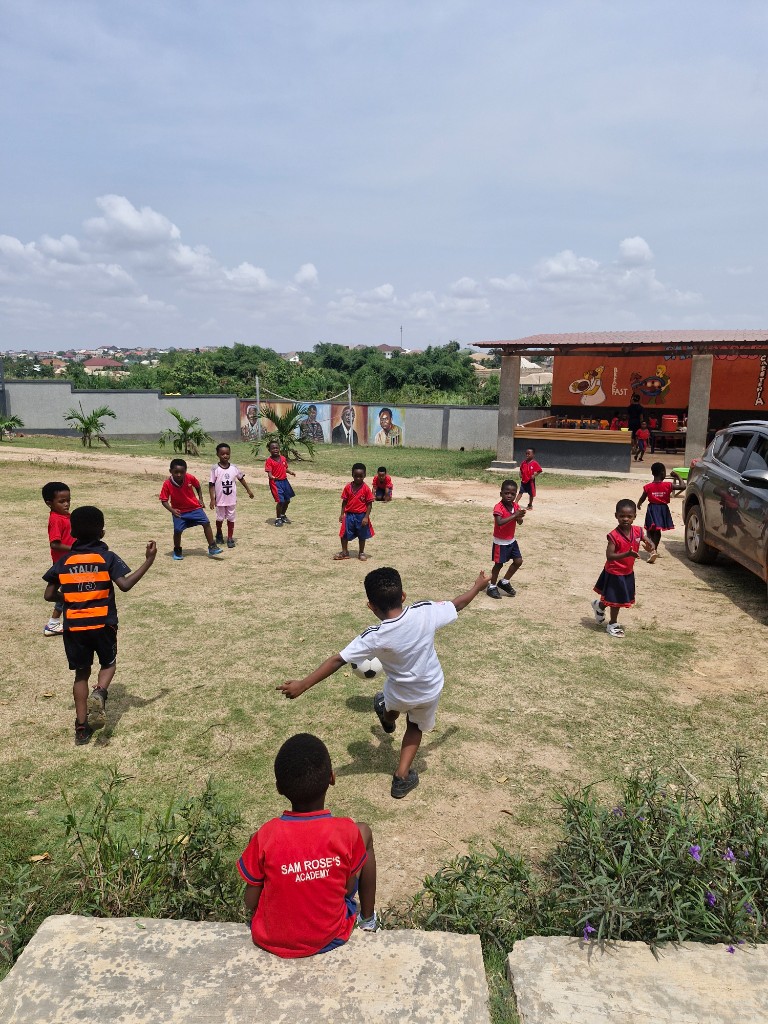 Pupils playing football on the school field beside the cafeteria